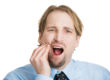 how to prevent tooth decay, blond man rubbing jaw