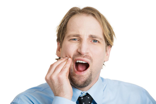 how to prevent tooth decay, blond man rubbing jaw