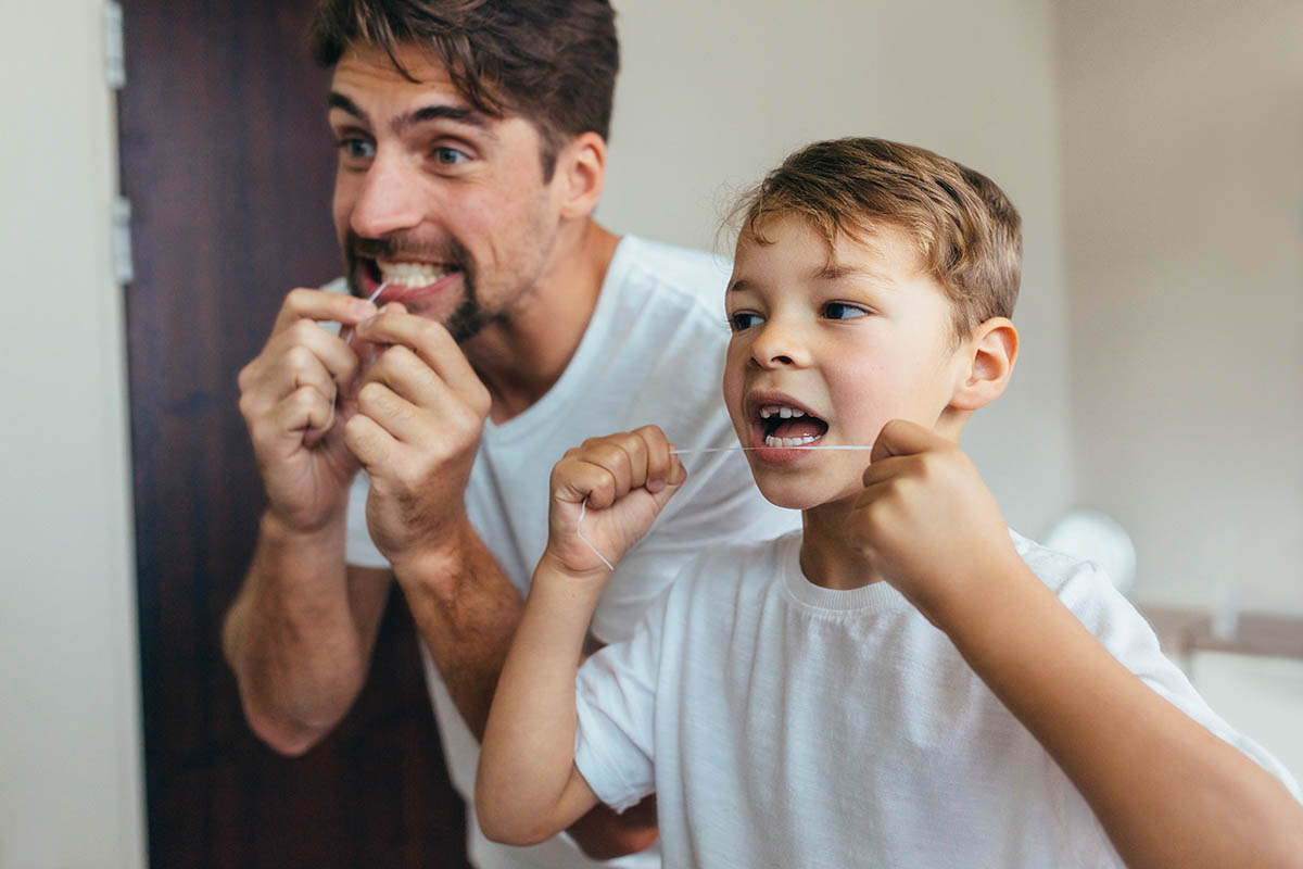 father and son flossing together showing benefits of flossing daily