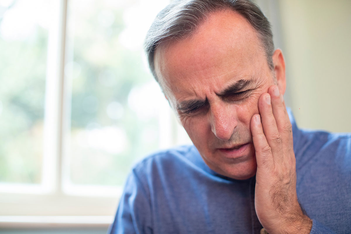 man holding jaw wondering how does tooth decay develop