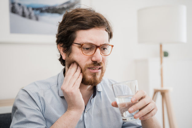 common dental problems man holding cheek experiencing common dental problems