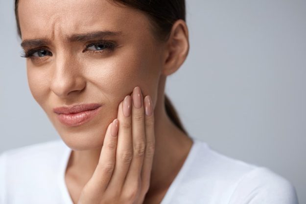 woman holding jaw in pain due to periodontal disease stages